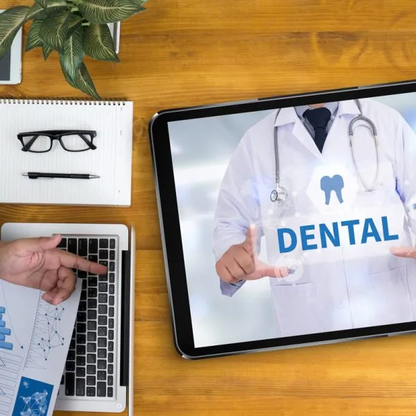 DENTAL INSURANCE Businessman working at office desk and using computer and objects, coffee, top view,