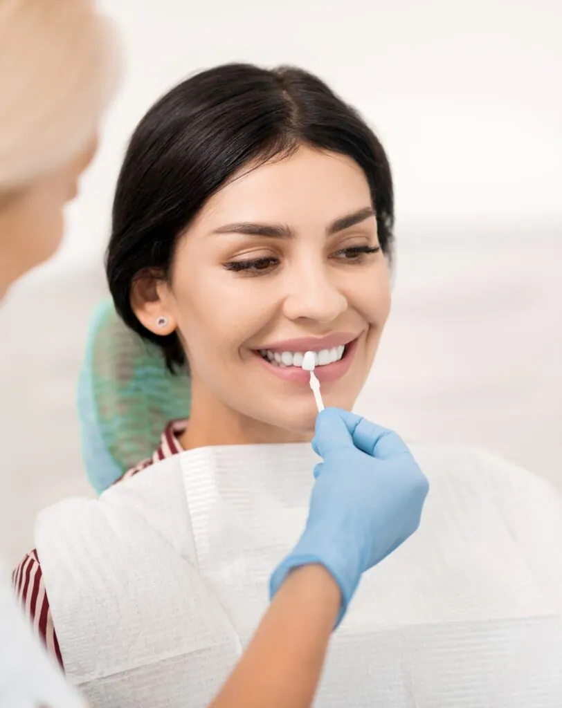 Mujer probando una muestra de blanqueamiento dental en el consultorio del dentista.