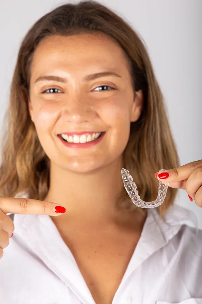 Mujer joven y feliz con un alineador dental invisible.