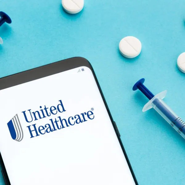 Galicia, Spain; June 8, 2021 : Unitedhealthcare logo on Smart phone screen pills and syringe on blue background